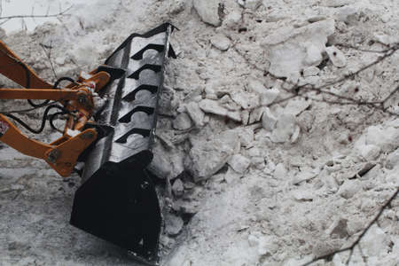 Modern yellow tractor with a large bucket clears the road from snow, snow removal, special equipment in the yardの写真素材