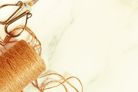 Decorative scissors and jute rope in a skein on a marble background. Tailoring concept background....