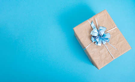 Gift box made of craft paper with a blue bow on a blue background