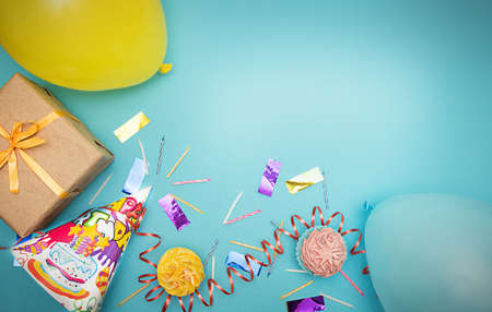 Letters with birthday accessories, candies and confetti on blue background. Flat lay with copy space