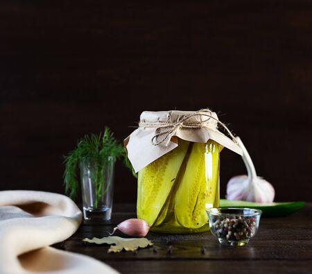 Fermented pickles in a glass jar on a dark wooden background. Ingredients for cooking.の写真素材