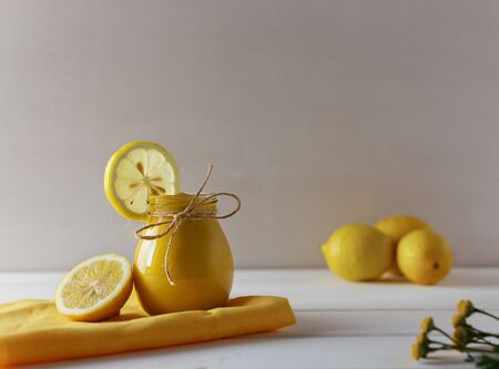 Homemade Lemon Curd made from eggs, lemon, butter and honey, in a glass jar on a white wooden backgroundの写真素材