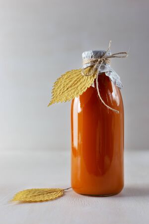 Bottle of fresh pumpkin juice on light wooden background. Vertical photo.の写真素材