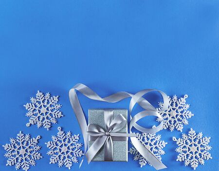 Christmas silver gift box with snowflakes on blue background with copy space. Top view. Greeting card for New Year.の写真素材