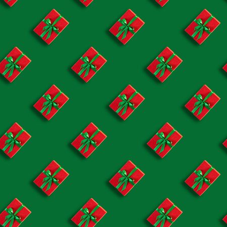 Seamless Christmas pattern with Xmas gift red box on green background. Flat lay. Top view.の写真素材