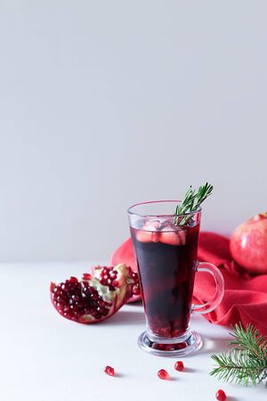 Pomegranate Christmas cocktail with champagne, soda and rosemary on a white table. Xmas drink. Close up. Copy space. Vertical orientation.の写真素材