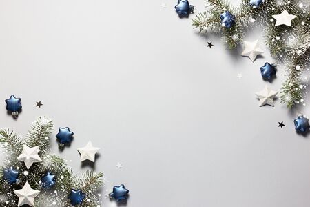Christmas snowy border of shiny balls and classic blue stars, evergreen branches on neutral pastel grey background. View from above. Flat lay. Xmas holiday. Template, mockup, greeting New Year card.の写真素材