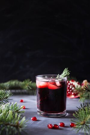 Pomegranate Christmas cocktail with champagne, club soda and rosemary on black table. Xmas drink. On the background are fir branches. Close up. Copy space. Vertical orientation.の写真素材