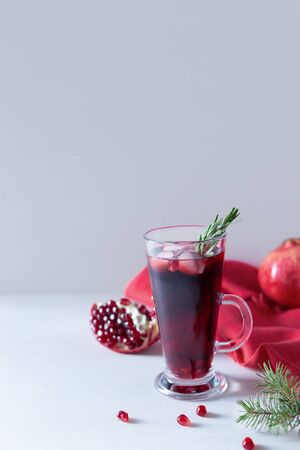 Pomegranate Christmas cocktail with champagne, soda and rosemary on a white table. Xmas drink. Close up. Copy space. Vertical orientation.の写真素材