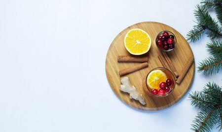 Orange and cranberry non-alcoholic punch with orange slices, cranberries, ginger root and cinnamon on neutral pastel grey background. Hot drinks for winter and Christmas. Flat lay. Copy space.の写真素材