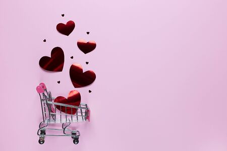 Shopping cart with love hearts on pink background with copy space. Valentine's day. Holiday of all lovers.の写真素材