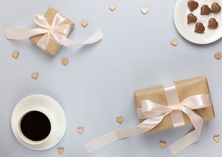 Festive banner of Valentine's Day. A Cup of coffee, a gift boxes and a heart-shaped chocolate on a neutral pastel grey background. Flat lay. Top view.の写真素材