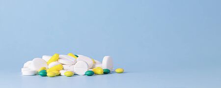 A bunch of different pills lying on a blue background. Front view with a copy space. Medical...