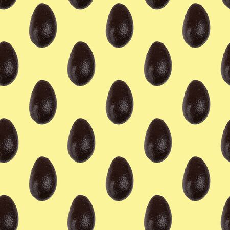 Seamless pattern of whole avocado isolated on a light yellow. Food background. Flat lay.