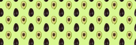 Seamless pattern of whole and half avocado isolated on green. Food background. Flat lay.の写真素材