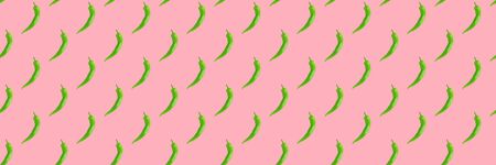 Seamless pattern of green hot chilli peppers on pink. Food background, texture. Minimal concept.の写真素材