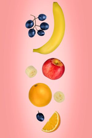 Falling apples, bananas, oranges, and grapes isolated on a pink background with clipping path as package design element and advertising. Flying fruit.の写真素材