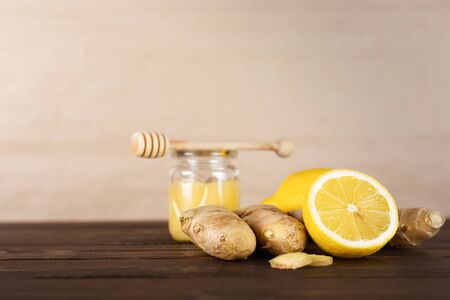 Ingredients for making healthy vitamin tea: honey, ginger root, lemon on a brown wooden table. Alternative medicine concept. Spices for ayurvedic treatment.の写真素材