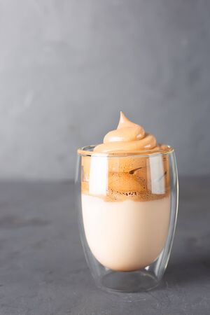 Korean iced Dalgona coffee in glass on a grey table. Trendy fluffy creamy whipped coffee.の写真素材