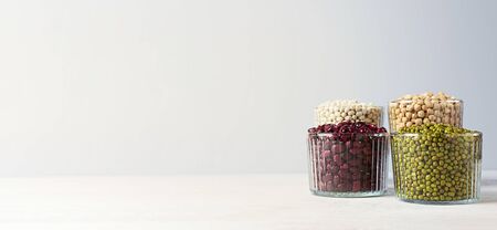 Bowls of various legumes: chickpeas, lentils, mung, red and white bean on a gray background with copy space. Banner.の写真素材