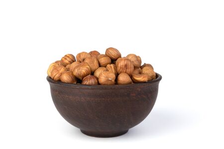 Hazelnuts in a brown clay bowl, isolated on a white background. Front view.の写真素材
