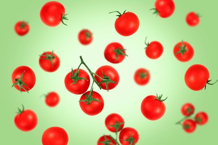 Falling red cherry tomatoes  on a green background    as package design element and advertising. Flying food.の写真素材
