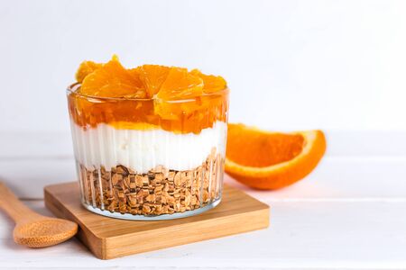 Dessert of yogurt, jam, orange and granola on a white wooden table. Healthy food. Breakfast.の写真素材