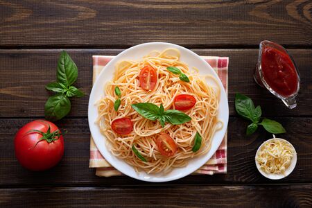 Delicious delicious pasta with tomato sauce, tomatoes and Basil on a wooden background. Concept of Italian cuisine. The view from the top.の写真素材