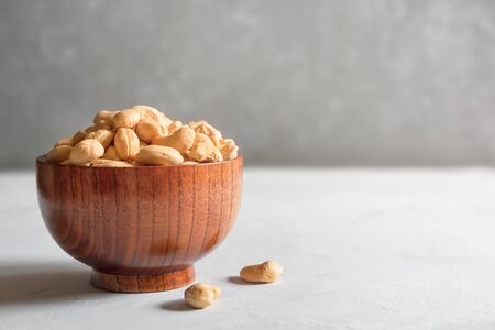 Cashews in a brown wooden bowl on a gray background with a copy of the space.の写真素材