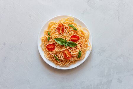 Pasta with cherry tomatoes, cheese and basil on a light background. Top view, copy space.の写真素材
