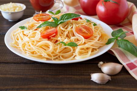 Delicious delicious pasta with tomato sauce, tomatoes and Basil on a wooden background. Italian food concept.の写真素材