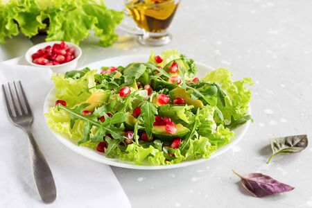 Avocado and pomegranate salad on a white plate on a gray background. Healthy vegetarian food.の写真素材
