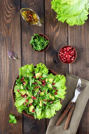 Avocado and pomegranate salad in a clay plate on a wooden background. Healthy food.の写真素材