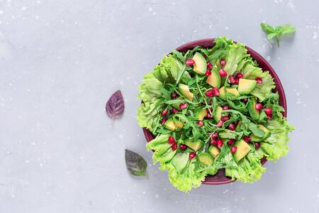 Avocado and pomegranate salad in a clay plate on a gray background. Healthy food. Top view.の写真素材