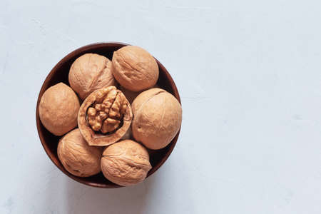 Walnuts in a brown wooden bowl on a gray background. Top viewの写真素材