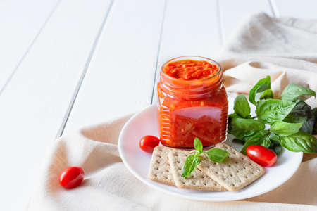 Balkan traditional dish ajvar, lutenitza, pingjur, with bread on a plate on white wooden table. Serbian traditional food.の写真素材