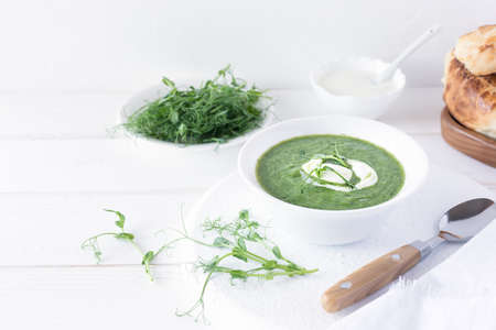 Broccoli and spinach cream soup, served with bread and micro greens in a white bowl. Healthy eating. Vegetarian and vegan foodの写真素材