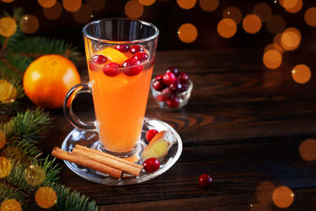 Orange and cranberry non-alcoholic punch with orange slices and spices on a dark wooden tableの写真素材