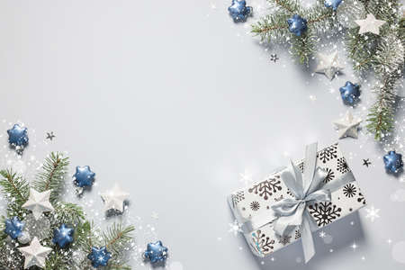 Christmas snow border gift box, shiny balls and stars, evergreen branches on a gray background. Christmas card.の写真素材