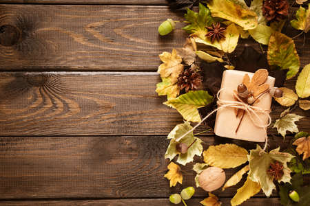 The concept of thanksgiving. Autumn background. A gift box decorated with acorns lies on dry leaves. Top view, copy space.の写真素材
