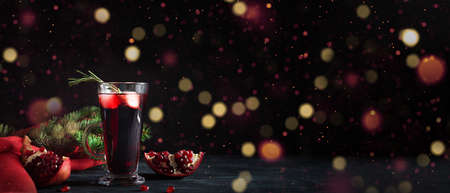 Pomegranate Christmas cocktail with rosemary, champagne, club soda on black table with bokeh lights. Xmas drink. Bannerの写真素材