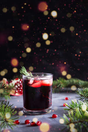 Pomegranate Christmas cocktail with rosemary, champagne, club soda on black table with bokeh lights. New year drinkの写真素材
