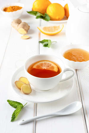 Antioxidant healthy tea with lemon, ginger, honey, turmeric and mint on a white wooden table. The concept of alternative medicine.の写真素材