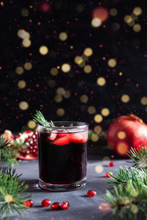 Pomegranate Christmas cocktail with rosemary, champagne, club soda on black table with bokeh lights. New year drinkの写真素材