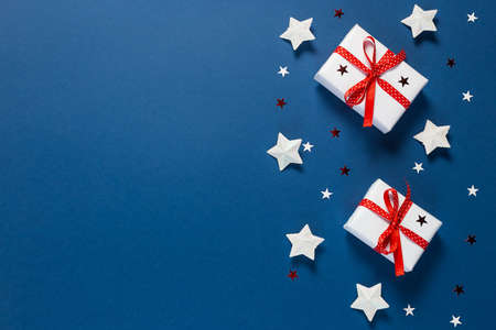 Christmas background. White gift boxes are tied with a red ribbon and Xmas toys in the shape of a star on a blueの写真素材