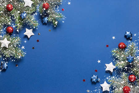 Christmas background with snow fir branches, shiny red balls, blue and white stars on a blue.の写真素材