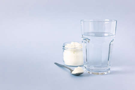 Collagen powder and a glass of water. Healthy lifestyle. Natural beauty and health supplement. Copy...