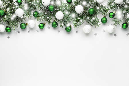 Christmas snow border of shiny white and green balls, evergreen branches on a white wooden background. New year card.の写真素材