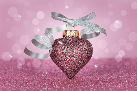 Christmas toy in the form of a heart on a pink bokeh background. Christmas card. Sparkling texture.の写真素材