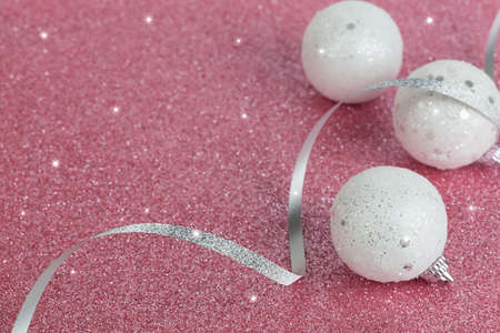 Christmas white balls on a pink sparkling background. New year card. Shiny texture. Selective focus.の写真素材